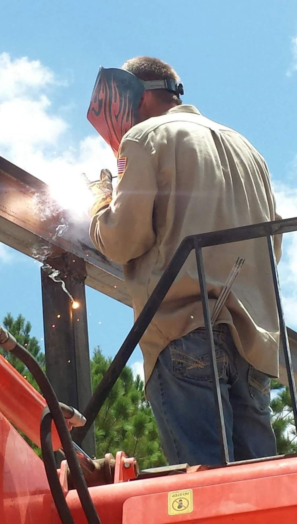 Aaron VanRiper welding structural steel on site from a lift