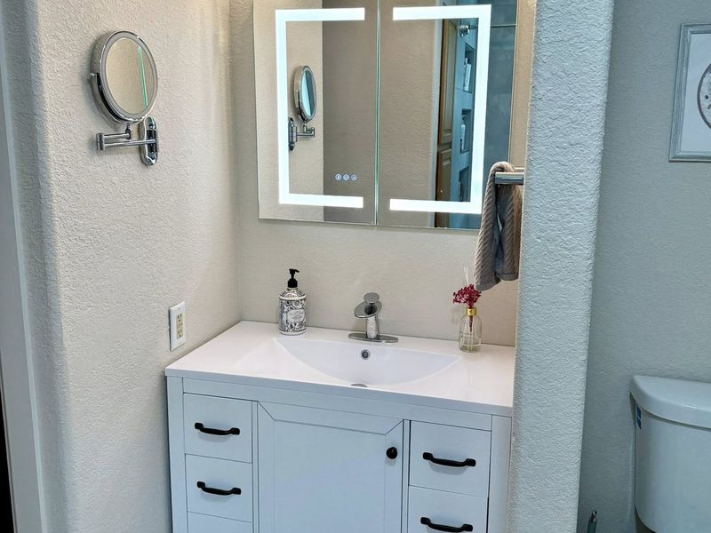 Rebuilt bathroom vanity with lighted mirror and new fixtures
