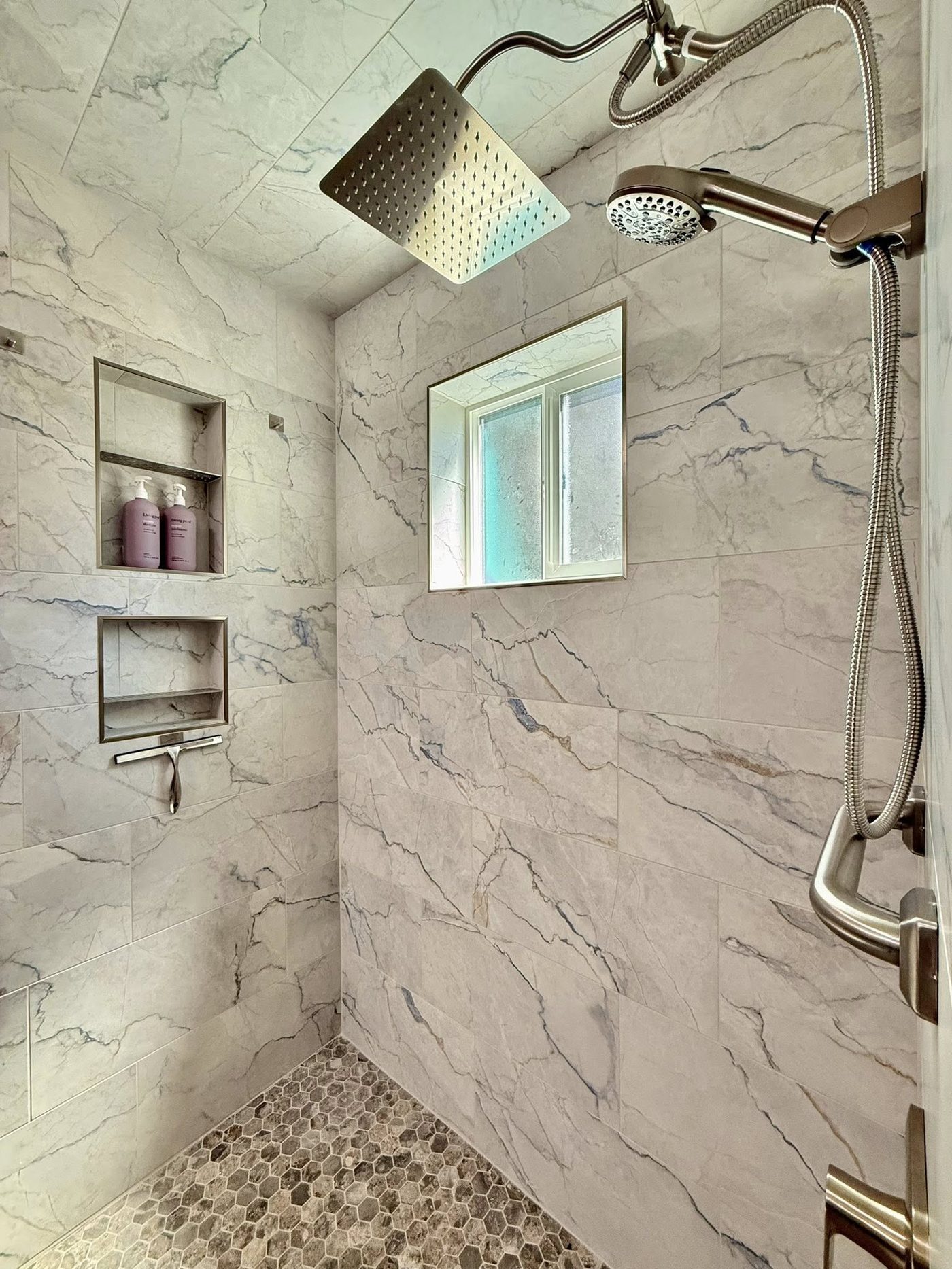 Inside the rebuilt shower: rain head, handheld wand and two tiled niches