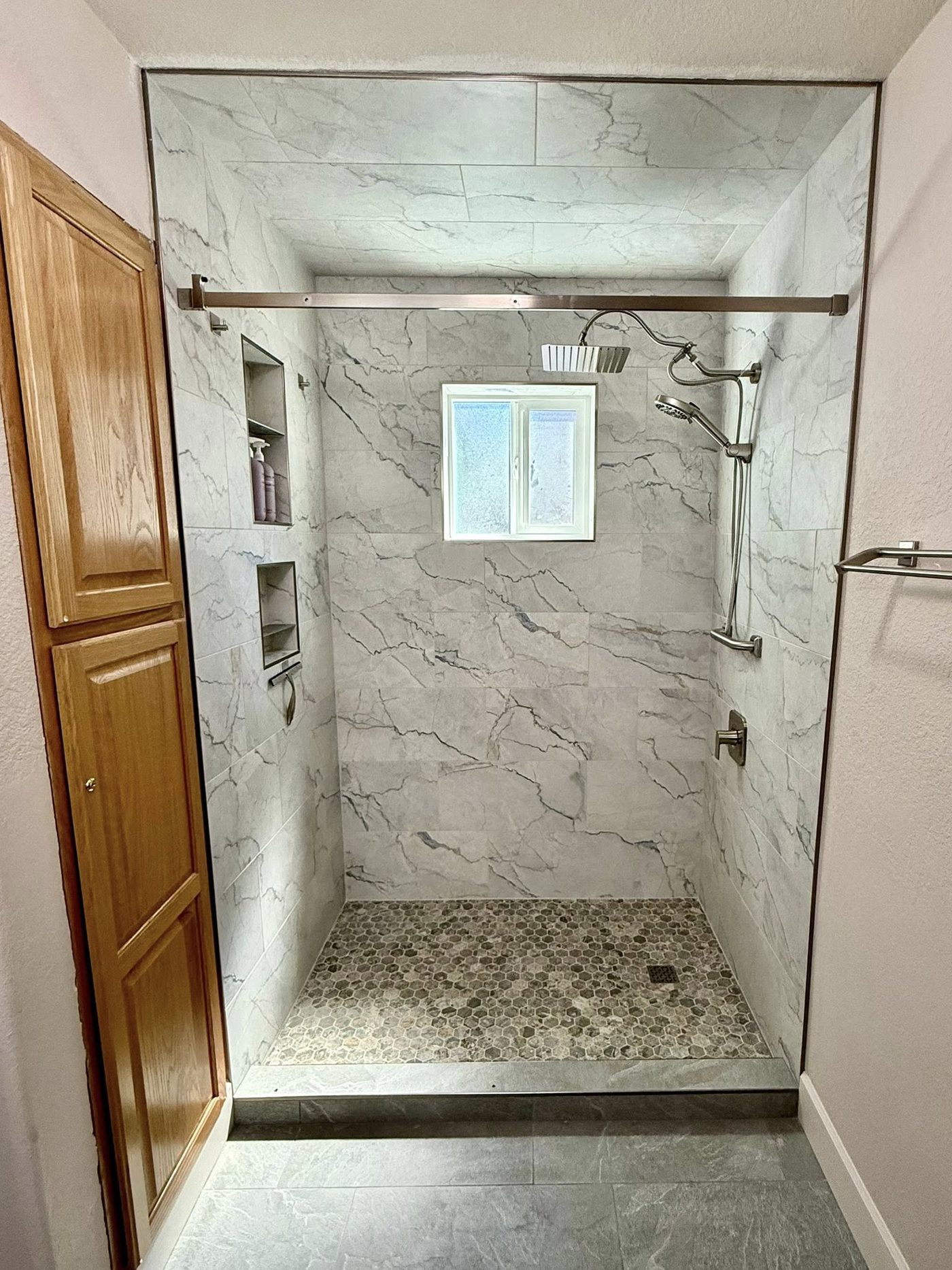 Rebuilt shower seen from the bathroom, with a slate-look tile floor