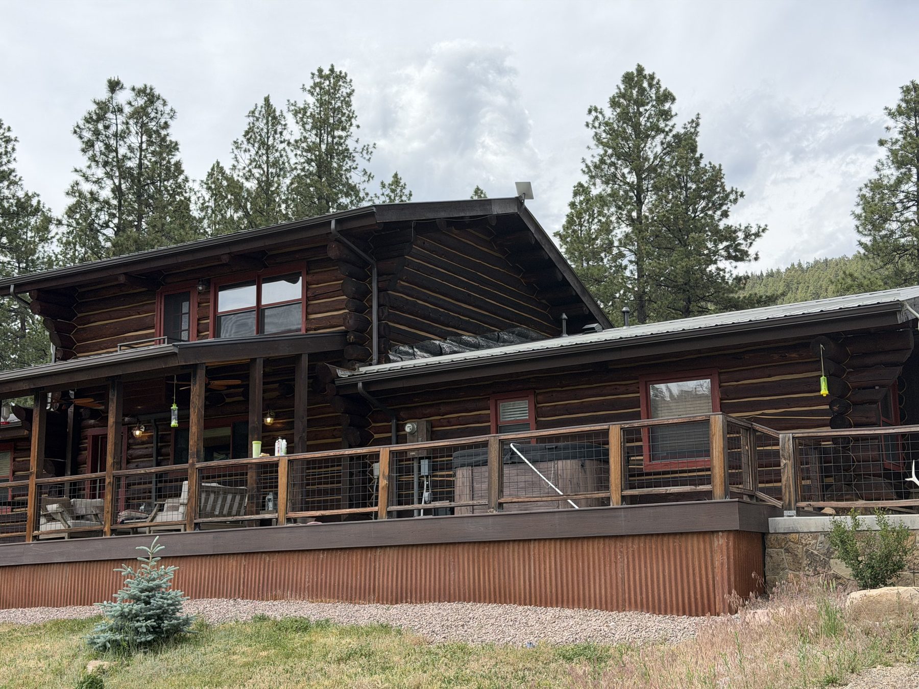 Log home with standing metal roofing and a wire-panel deck railing