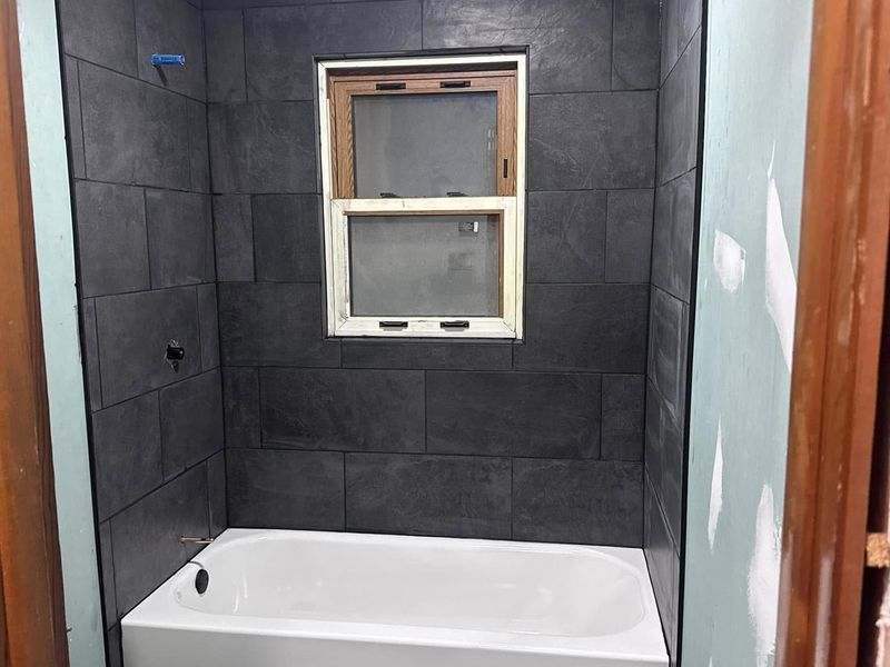 Finished bathroom remodel with a large-format slate tile tub surround and floor