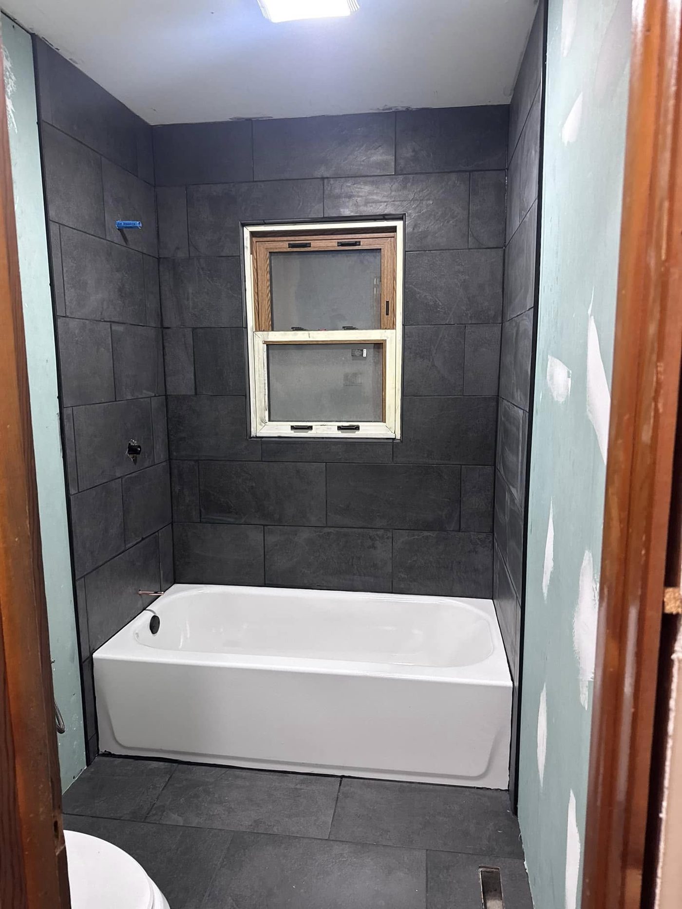 Finished bathroom remodel with a large-format slate tile tub surround and floor
